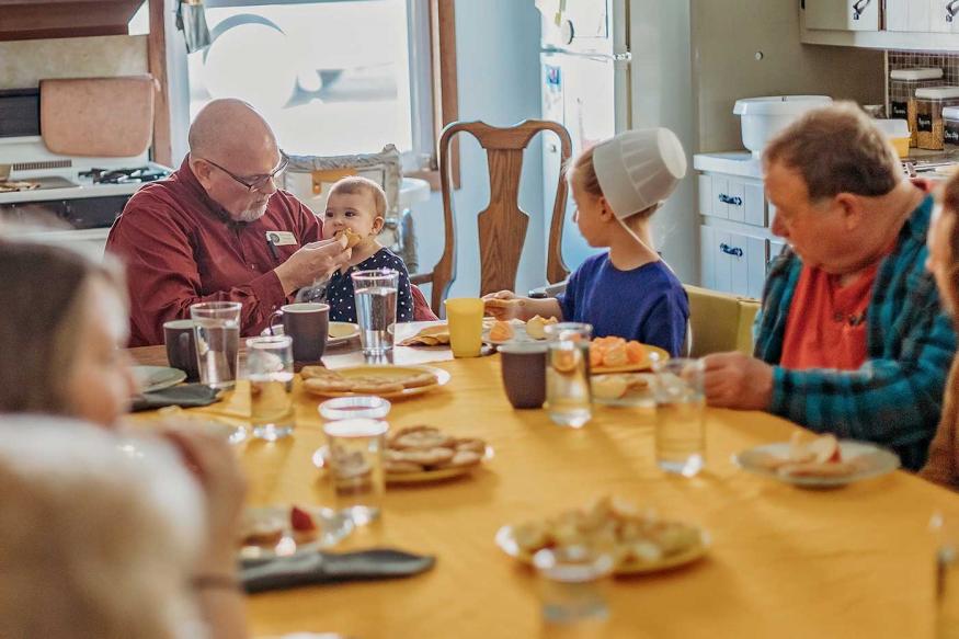 Group of tourists sharing a meal with an Amish family