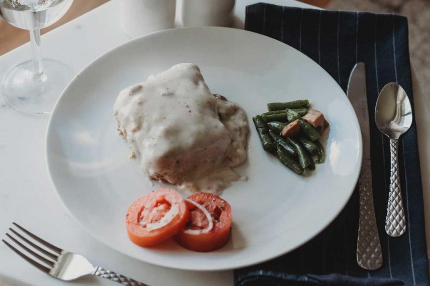Fancy presentation of tomatos, green beans, and a biscuit with sausage gravy