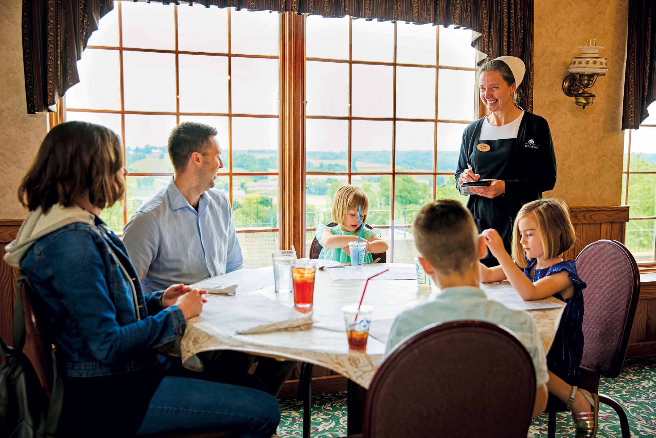Amish waitress greeting a table of guests at Der Dutchman Restaurant.