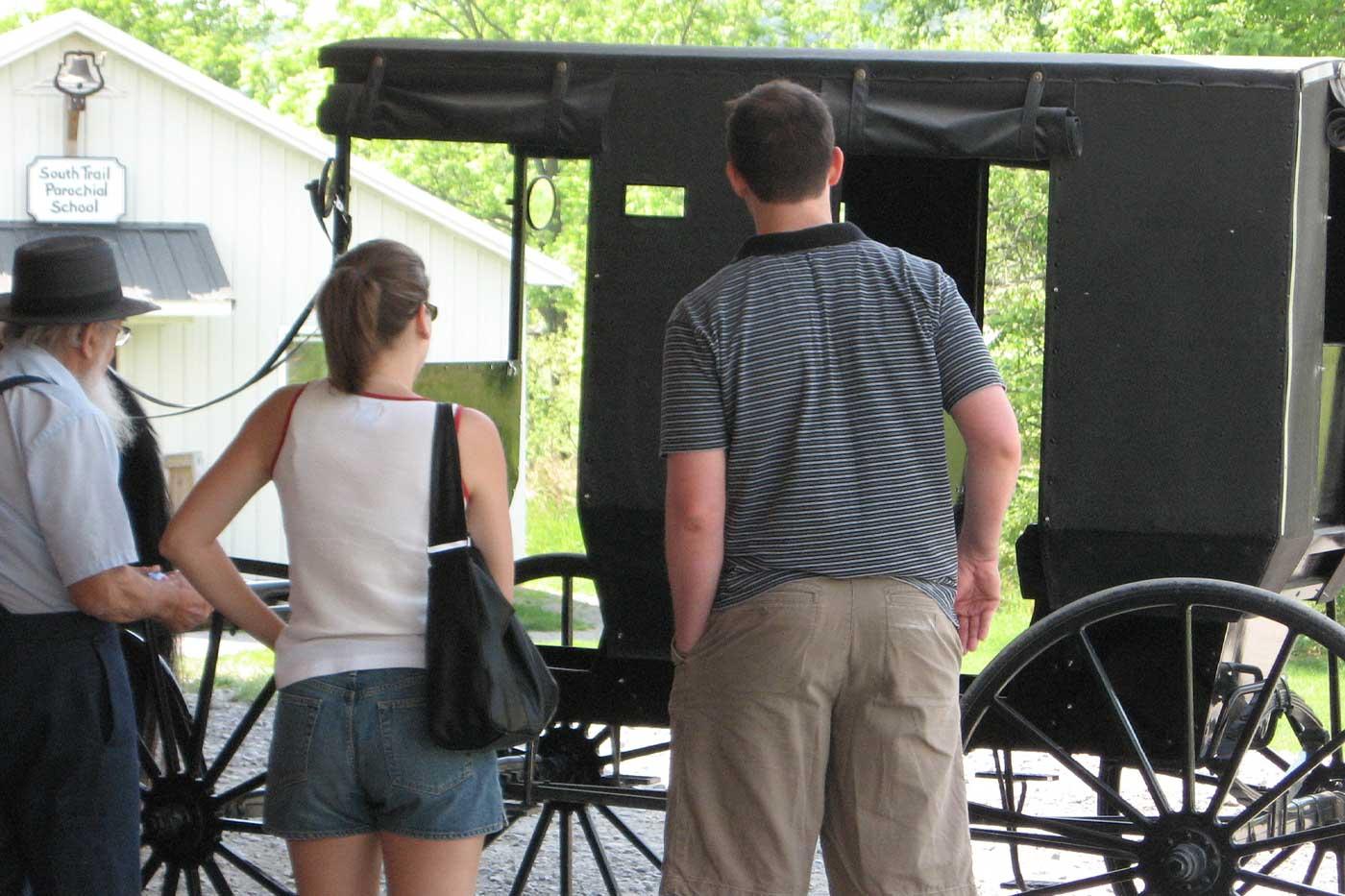 Tourist couple learning about an Amish buggy from an Amish man